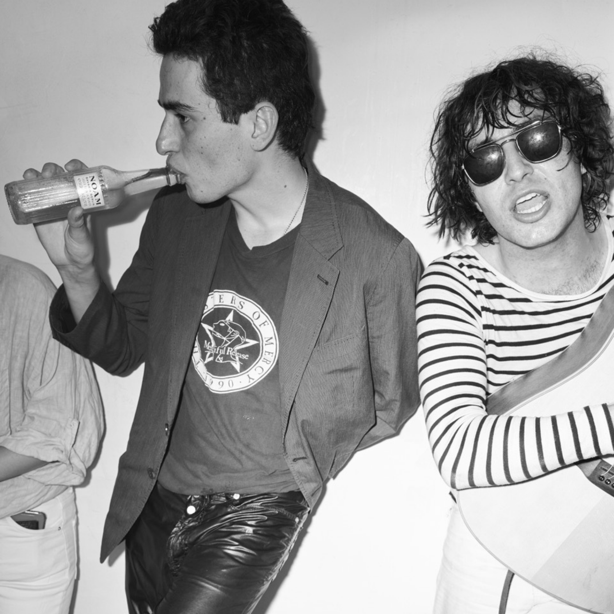 Two people in a casual setting, one drinking from a bottle and the other wearing sunglasses and a striped shirt.