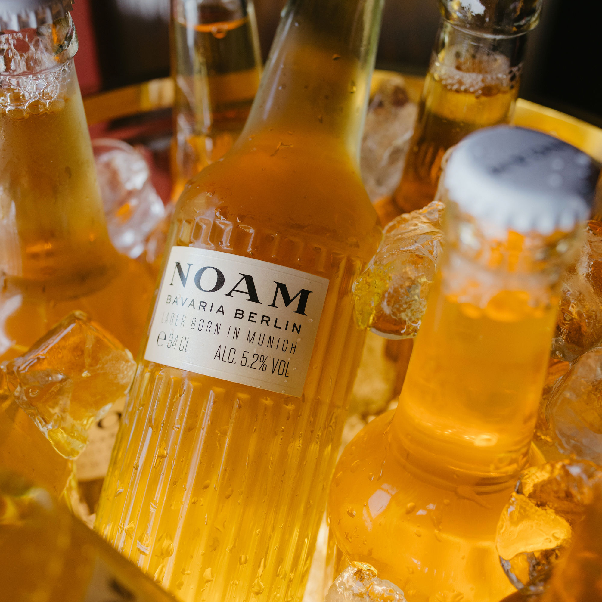 Bottle of NOAM beer with a label on a table with ice cubes