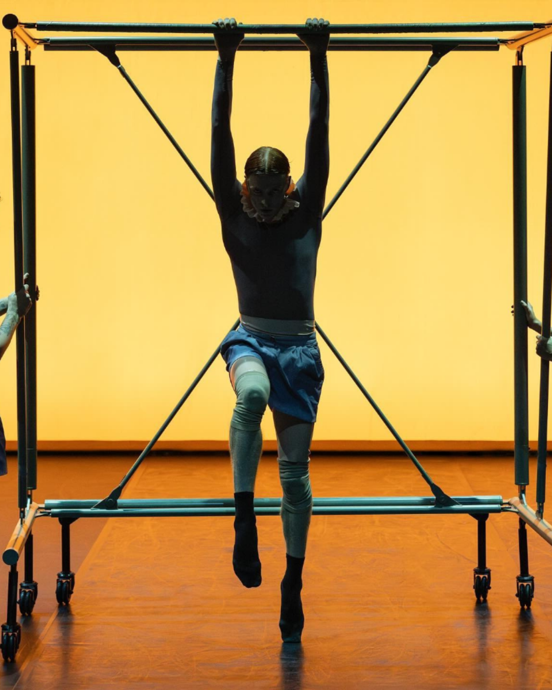 Person exercising on a pull-up bar against a yellow wall