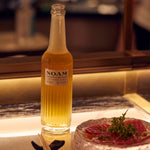 Bottle of NOAM beer on a bar counter with a blurred background