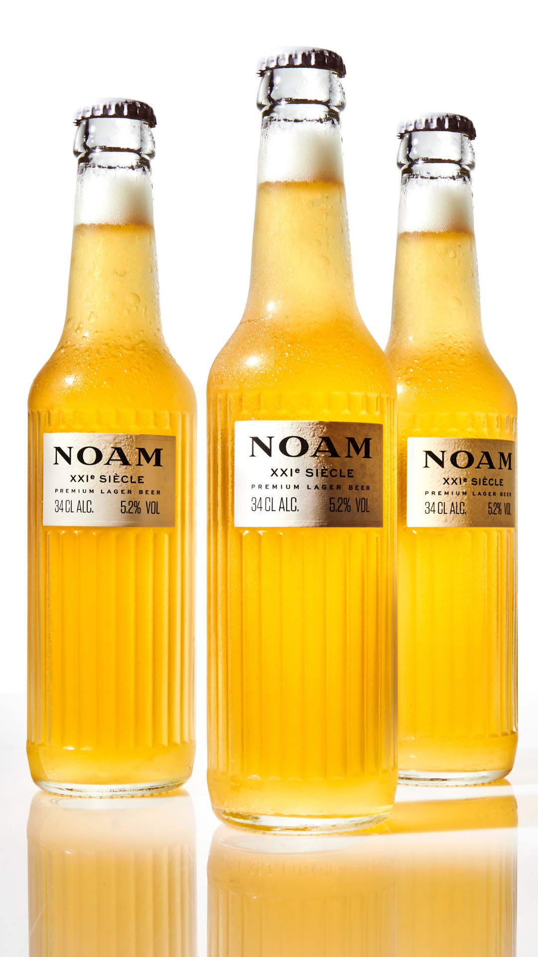Three bottles of NOAM apple cider on a white background