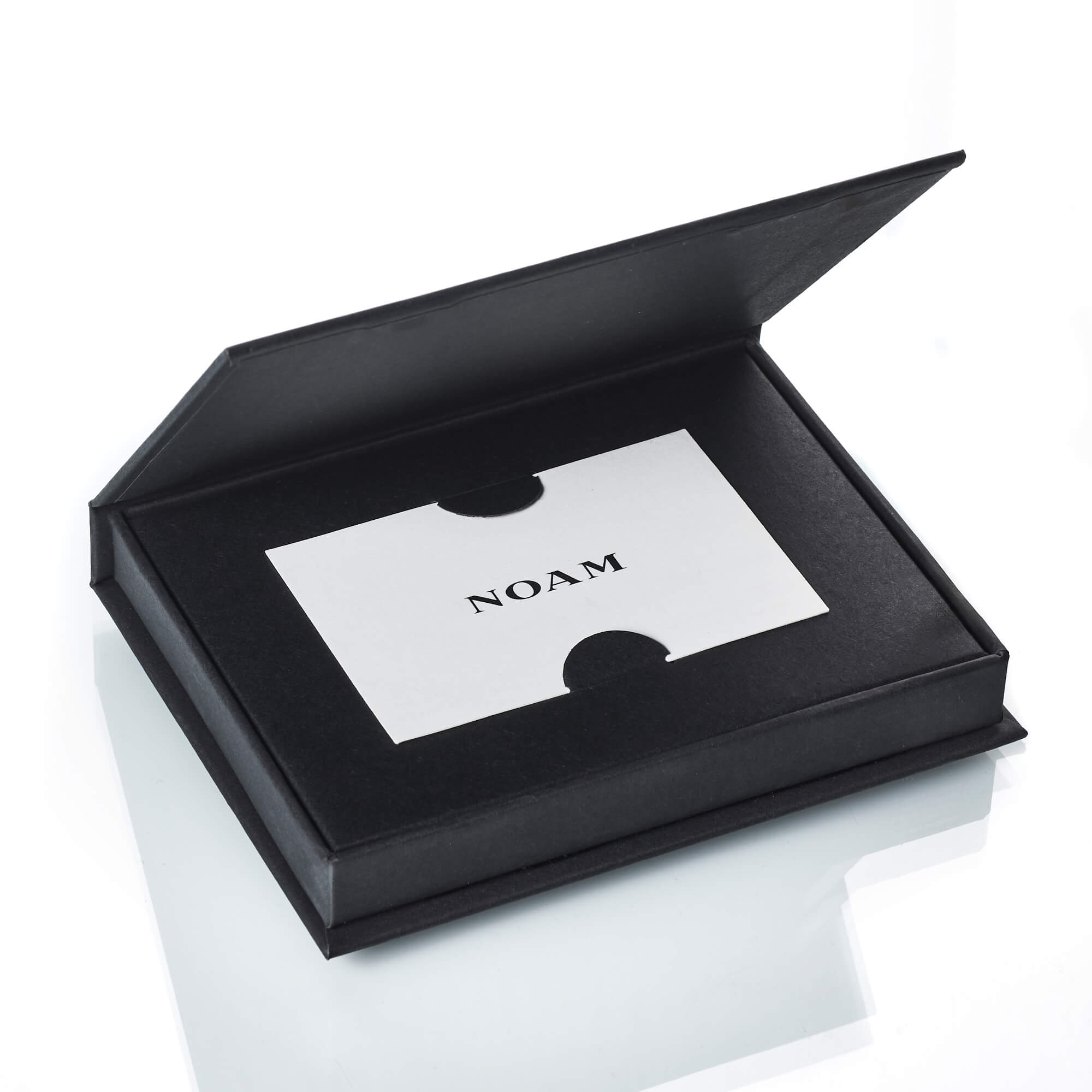 A NOAM gift card displayed in an open black gift box on a white background.