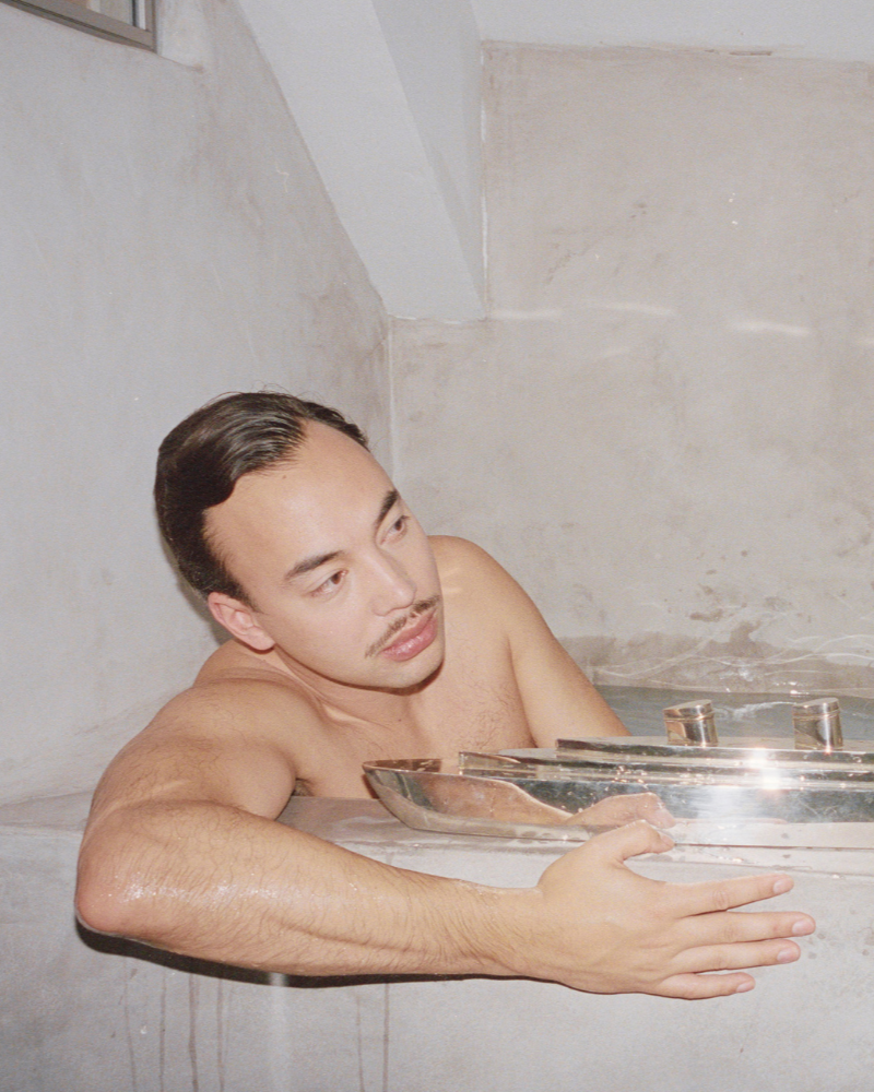 Man sitting in a hot tub with steam rising, surrounded by metal railings.