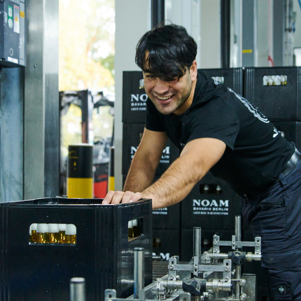 Person working with a crate of bottles in a brewery setting